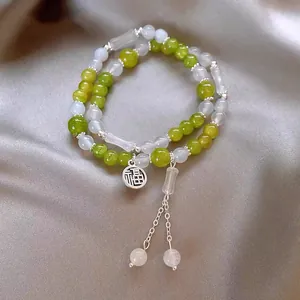 Detail of Chinese style beaded bracelet with green and white stones and Fu charm