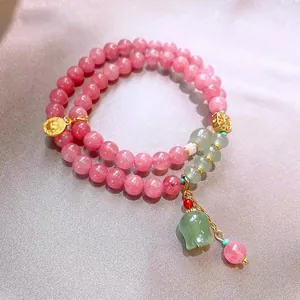 Close-up detail of a pink quartz and green jade style double-loop beaded bracelet