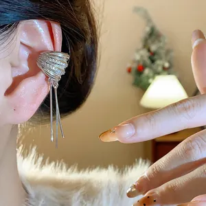 Detalle de un manguito de oreja plateado con circonitas y borlas de varias capas en la oreja