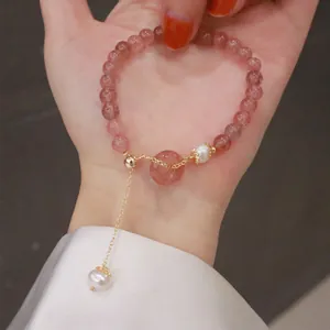 Macro view of strawberry quartz crystal beaded bracelet with elegant pearl charm on palm