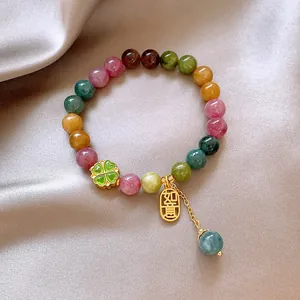 Close-up detail of a colorful beaded bracelet with a green four-leaf clover and Ruyi charm