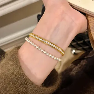 Elegant zircon and pearl bracelets worn together for a sophisticated layered look.
