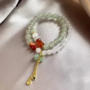 Close-up of elegant Chinese style beaded bracelet with gold Fu charm and green bamboo.