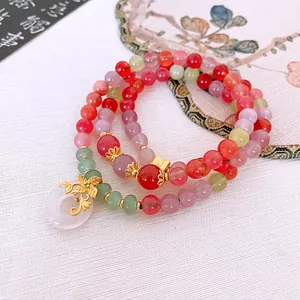 Detail shot of a multi-layer beaded bracelet with pink pendant and gold charm