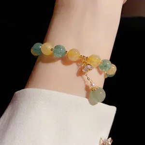 Close-up view of a feminine beaded crystal heart bracelet with green and yellow gemstones