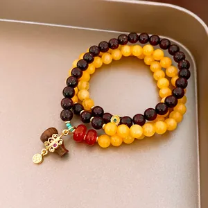 Close-up of multi-strand beaded bracelet featuring dark garnet and yellow agate beads.