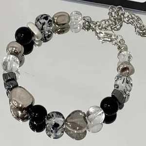 Detailed close-up of a stylish beaded bracelet featuring a grey transparent heart-shaped charm