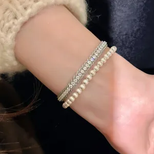Elegant detail showing a double-layer bracelet with zircon and pearls on a wrist