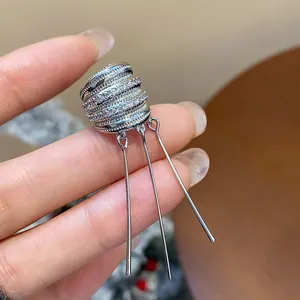Primer plano de un ear cuff de circonio plateado con borlas largas y rectas de moda