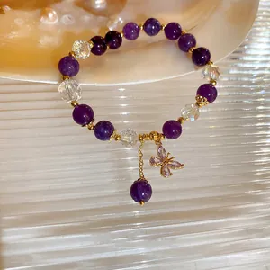 Detailed macro shot of a purple crystal beaded bracelet featuring a dainty butterfly charm.