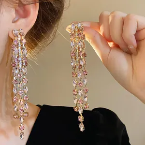 Primo piano di eleganti orecchini a nappa lunga in strass rosa scintillanti con ago d'argento