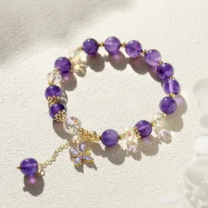 Close-up of an amethyst and crystal beaded bracelet featuring a butterfly charm