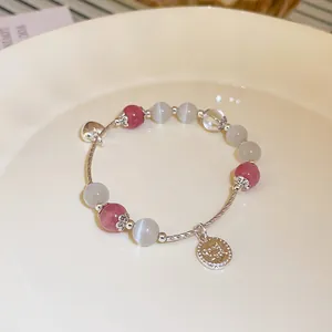 Close-up view of a pink and white beaded crystal bracelet featuring silver heart and coin charms
