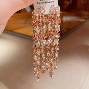 Primo piano dettagliato di eleganti orecchini a nappa lunga con cristalli rosa e chiari.