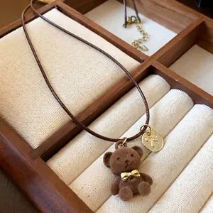 Simpatica collana con orsetto floccato marrone con ciondolo a fiocco dorato e cuoio