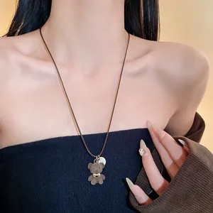 Dettaglio di una graziosa collana con orsetto marrone floccato e fiocco dorato su corda