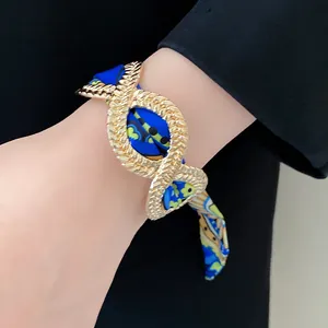 Close-up of a French retro gold alloy bracelet with blue patterned silk scarf