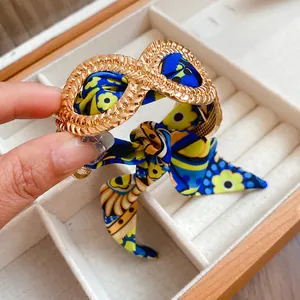 Detailed macro view of an exotic alloy gold bangle with a floral silk scarf ribbon