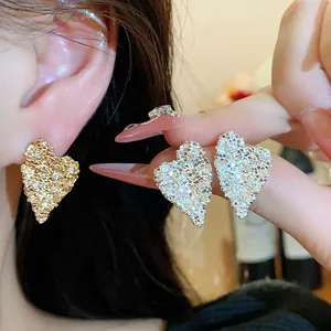 Dettaglio di eleganti orecchini a lobo a forma di cuore in oro e argento con zirconi