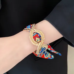 Close-up detail of a vintage alloy bracelet with colorful geometric silk scarf ribbon