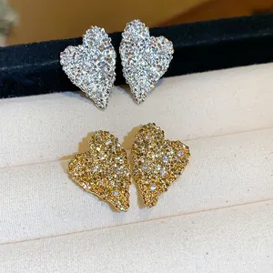 Primo piano di orecchini a lobo a cuore con zirconi, finiture in oro e argento