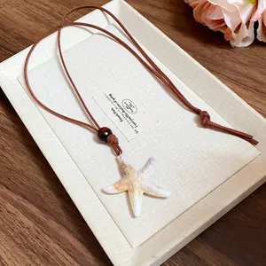 Gros plan sur le collier pendentif étoile de mer vintage avec perle en bois brun