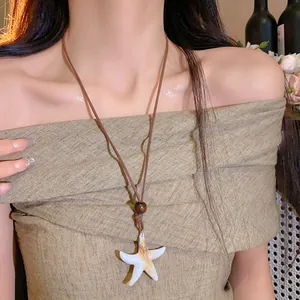 Gros plan d'un collier avec pendentif étoile de mer blanche et perle de bois sur cordon