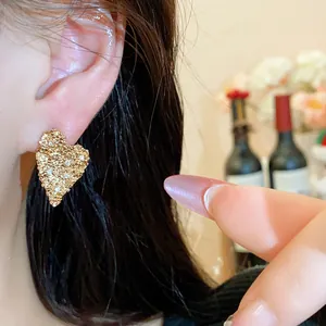 Dettaglio orecchini a lobo a cuore placcati in oro 18K con trama stropicciata e zirconi