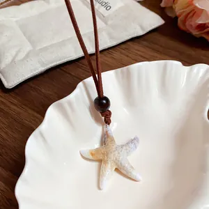 Détail d'un collier vintage avec pendentif étoile de mer en acrylique sur un plateau en coquille