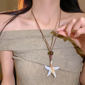 Gros plan sur un collier vintage avec pendentif étoile de mer et perle en bois mat