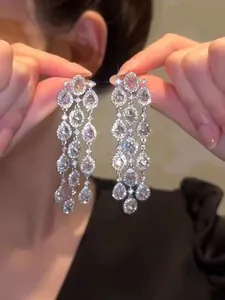 Detailed close-up view of elegant sparkling zircon water-drop tassel earrings held by hand
