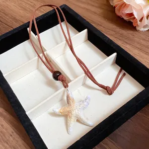 Détail d'un pendentif étoile de mer réaliste avec un cordon en daim marron élégant