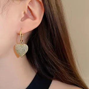 Close-up view of a gold-colored heart-shaped earring encrusted with shimmering rhinestones