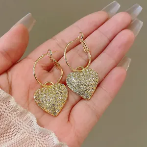 Detailed view of gold-tone heart hoop earrings encrusted with sparkling rhinestones