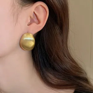 Detailed view of vintage oversized gold geometric stud earring worn on model's ear