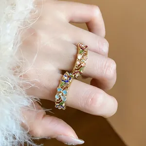 Detailed close-up of a gold-plated ring featuring colorful enamel flowers and inset crystals