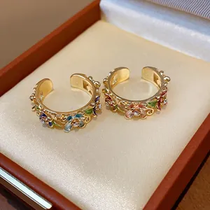 Close-up of 18k gold plated rings with floral enamel patterns and sparkling rhinestones