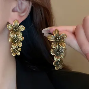 Close-up of vintage gold tiered flower earrings showing brushed metal texture.