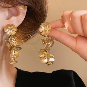 Détail de boucles d'oreilles fleurs vintage dorées avec un fini mat élégant