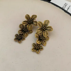 Detailed view of vintage gold tiered flower earrings with antique textured petals