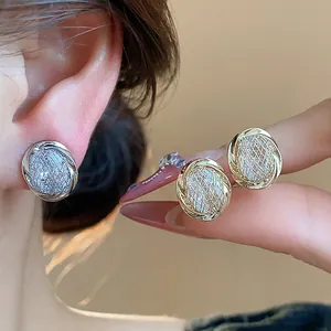 Close-up detail of 18k gold plated geometric clip-on earrings with elegant woven textures