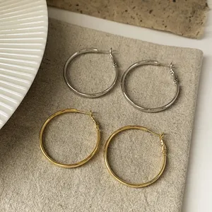 Nahaufnahme von eleganten gold- und silbernen Metall-Creolen auf beigem Leinenstoff