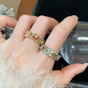 Close-up of retro 18k gold plated rings featuring colorful enamel floral designs on hand