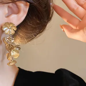 Élégantes boucles d'oreilles pendantes à fleurs dorées vintage portées par un mannequin