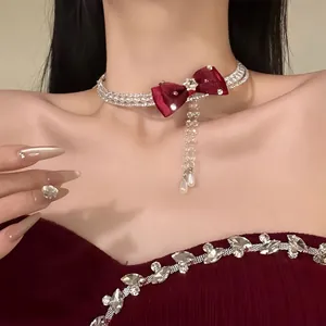 Close-up of an elegant pearl choker with a red bow and rhinestone tassels on a model