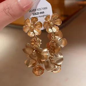 Vue détaillée d'élégantes boucles d'oreilles vintage en forme de fleurs dorées à franges.