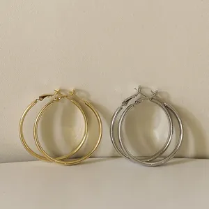 Detailansicht großer gold- und silberfarbener Metallcreolen in minimalistischem Design