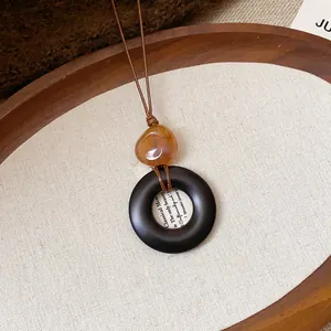 Primo piano del pendente della collana in resina in stile etnico su sfondo di tela bianca