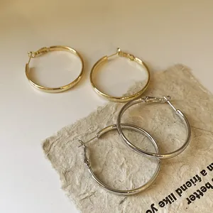 Nahaufnahme von minimalistischen Creolen aus Gold und Silber auf strukturiertem Papier.