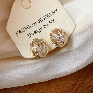 Macro detail showing 18k gold plated geometric zircon ear clips on a luxury display card